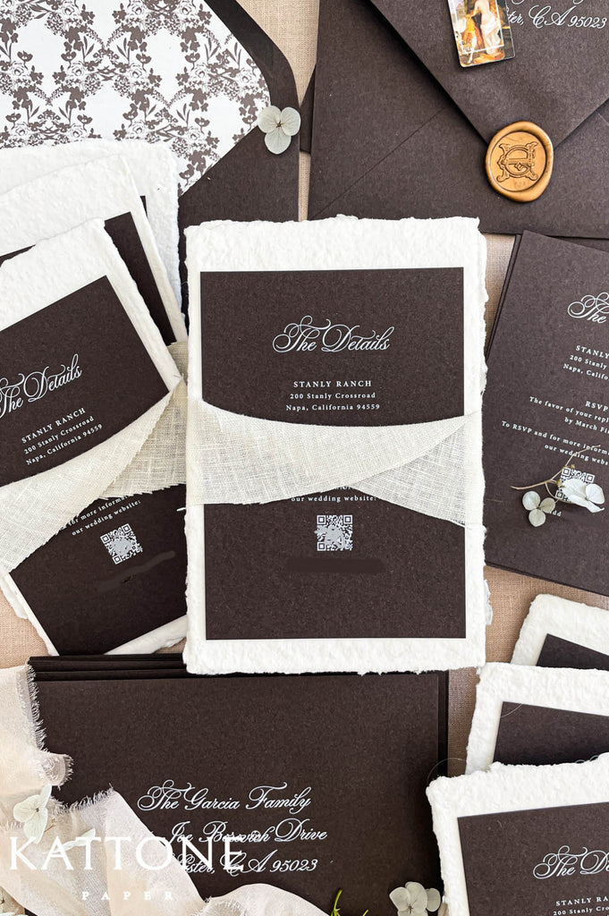 Fine art wedding invitation suite styled in flat lay with handmade paper invitations, inserts, envelopes and ribbon accents.