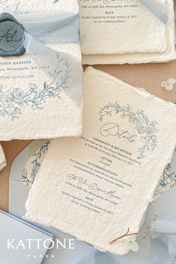 Elegant handmade paper wedding invitation with deckled edges featuring refined typography and romantic blue floral artwork.