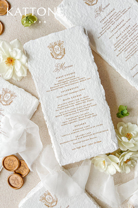 These handmade paper wedding menus with a custom monogram bring timeless elegance and refined craftsmanship to your wedding tablescape. Meticulously crafted from 100% cotton rag paper, each menu features natural deckled edges and a soft, luxurious texture that exudes artisanal charm. The custom monogram or crest - printed in elegant gold foil - adds a personal and regal touch, making every detail feel truly bespoke.