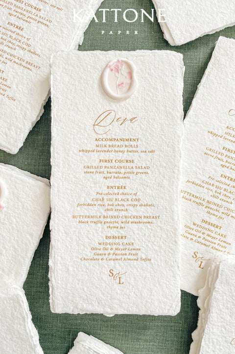 Handmade paper wedding menu with deckled edges, elegant typography, and wax seal detail, fine art reception stationery flat lay.