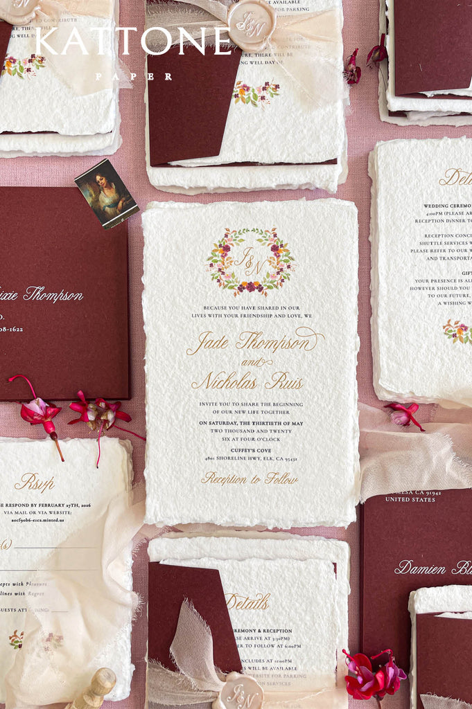 Flat lay of luxury wedding stationery including handmade paper invitations, RSVP cards, and details cards.