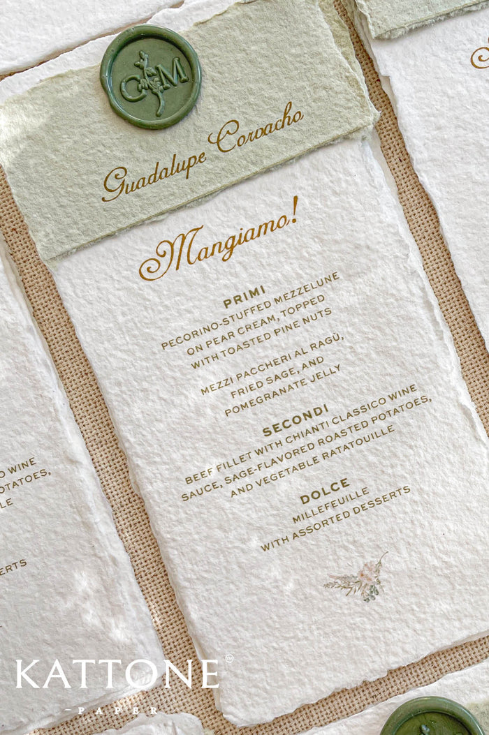 Handmade paper wedding menu with deckled edges, elegant serif typography, wax seal accent, luxury reception stationery flat lay.