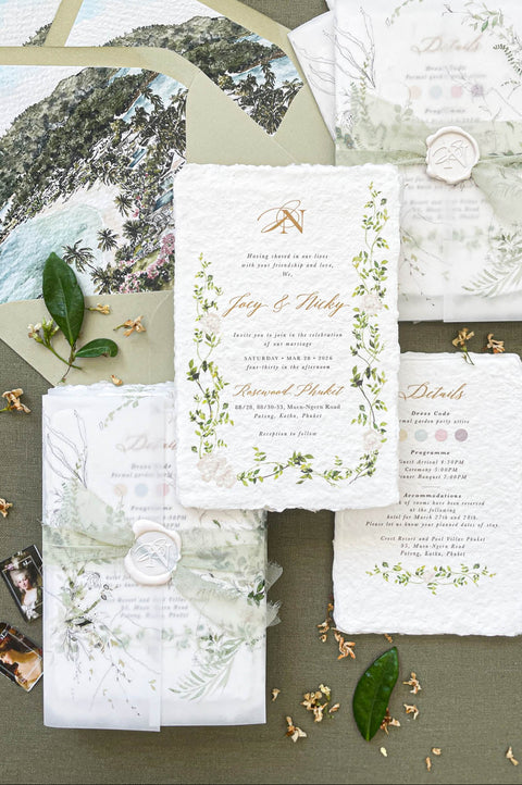 Handmade paper botanical wedding invitations with vellum wrap, deckle edge cotton paper, and greenery illustration.