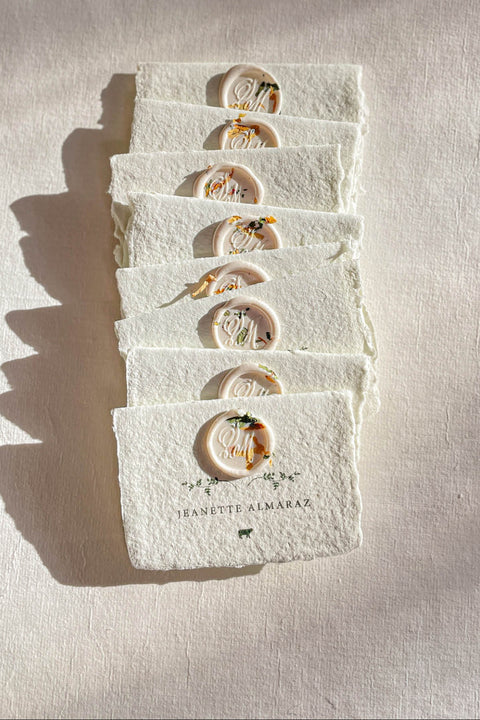 Elevate your table setting with our fine-art handmade paper place cards, each adorned with an elegant pressed-flower wax seal and delicate botanical artwork. Crafted from luxury deckled-edge cotton paper, these name cards bring a romantic, organic charm to weddings, garden celebrations, and intimate events. Their soft sage tones and artisanal texture create an unforgettable, heirloom-quality detail for your guests.