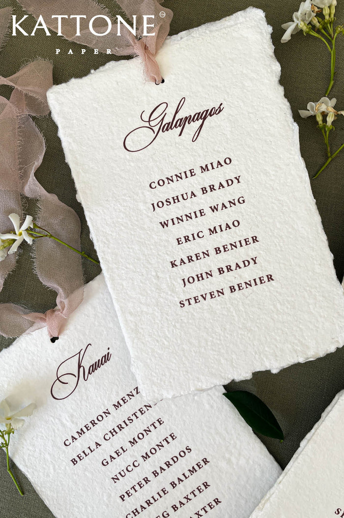 Handmade paper wedding place cards with deckle edges and elegant guest name typography.