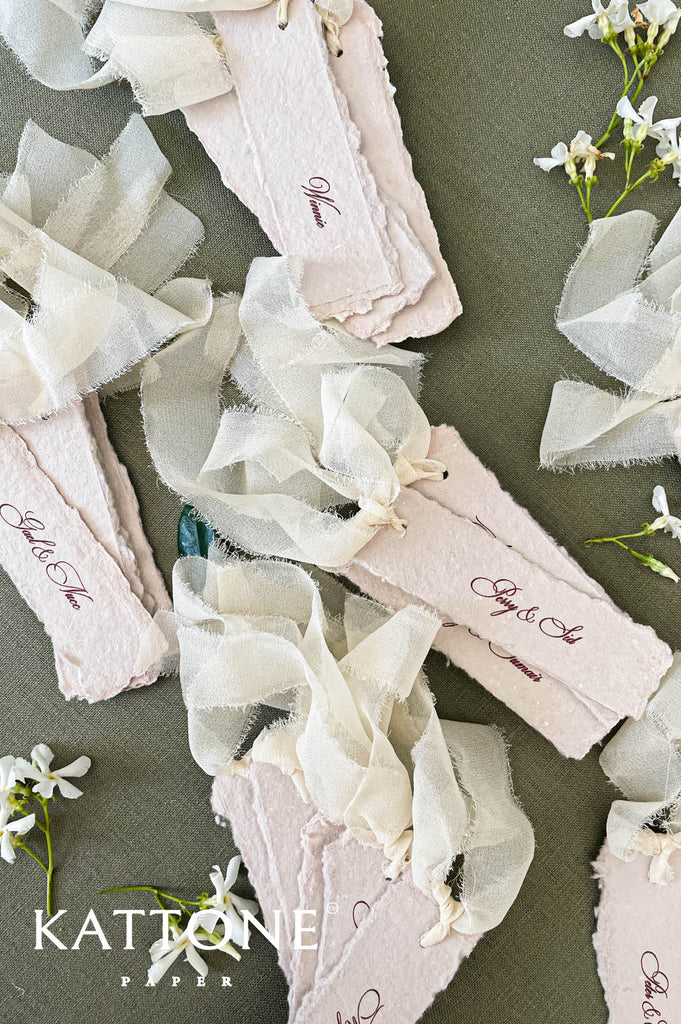 Blush handmade wedding place cards tied with soft ribbon for romantic table décor.