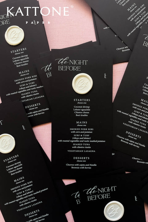 Close-up of black wedding menu showing clean typography and wax seal accent.