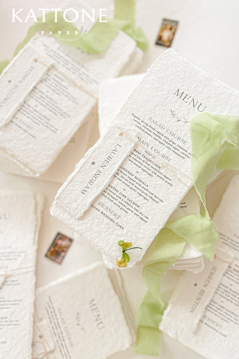 Bring a touch of natural elegance to your wedding reception with our handmade paper wedding menus, crafted from 100% cotton paper with softly torn deckled edges. Each piece exudes fine-art charm and artisanal craftsmanship, perfect for couples who appreciate timeless design and understated luxury. Paired with a sage green silk ribbon and a personalized guest name tag.