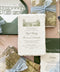 Luxury handmade paper wedding invitation suite featuring deckled edge cotton paper, custom venue sketch illustration, scenic vellum wraps, sage green envelopes, and powder blue chiffon ribbon styling.