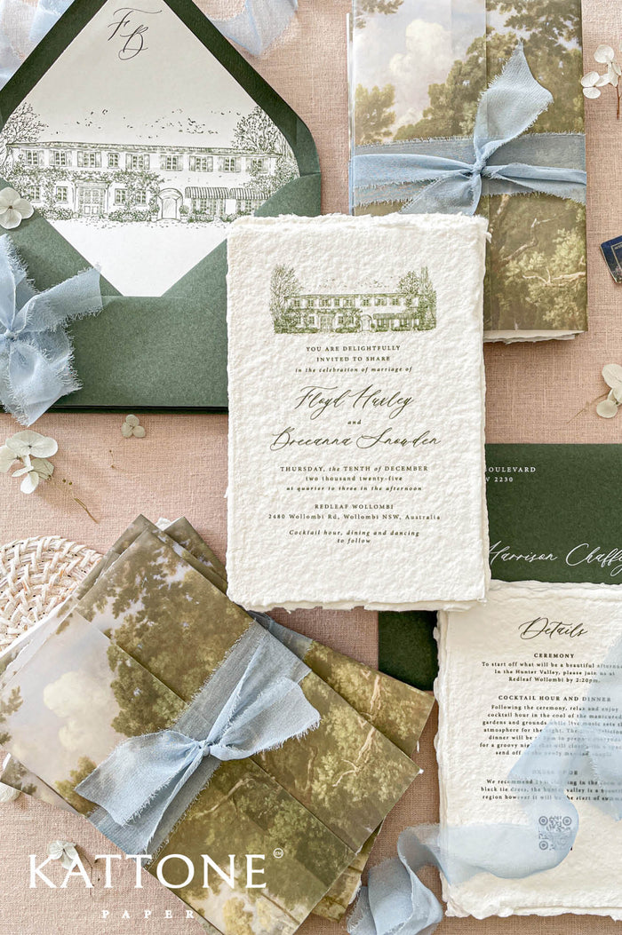 Luxury handmade paper wedding invitation suite featuring deckled edge cotton paper, custom venue sketch illustration, scenic vellum wraps, sage green envelopes, and powder blue chiffon ribbon styling.
