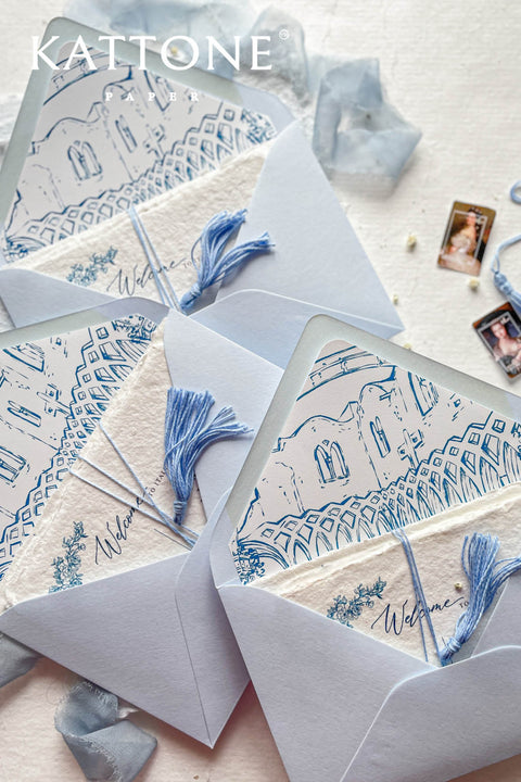Stack of light blue envelopes with illustrated venue liners visible, highlighting consistent artwork and premium stationery quality.