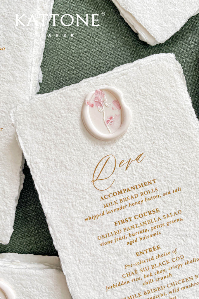 Close-up of handmade cotton paper wedding menu featuring delicate wax seal accent and refined lettering.