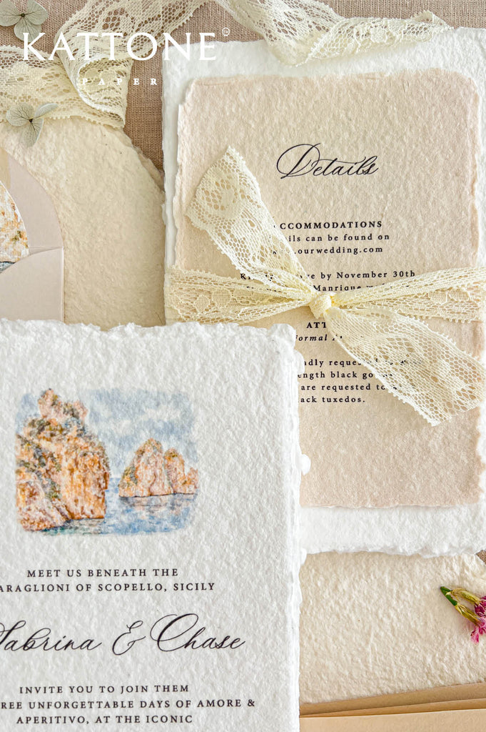 Close-up of an elegant champagne handmade paper wedding details card featuring delicate black calligraphy, classic typography, naturally deckled edges, and an intricate ivory lace bow. Coordinating white handmade paper and a matching invitation with a soft coastal watercolor illustration complete the romantic Mediterranean wedding stationery arrangement.
