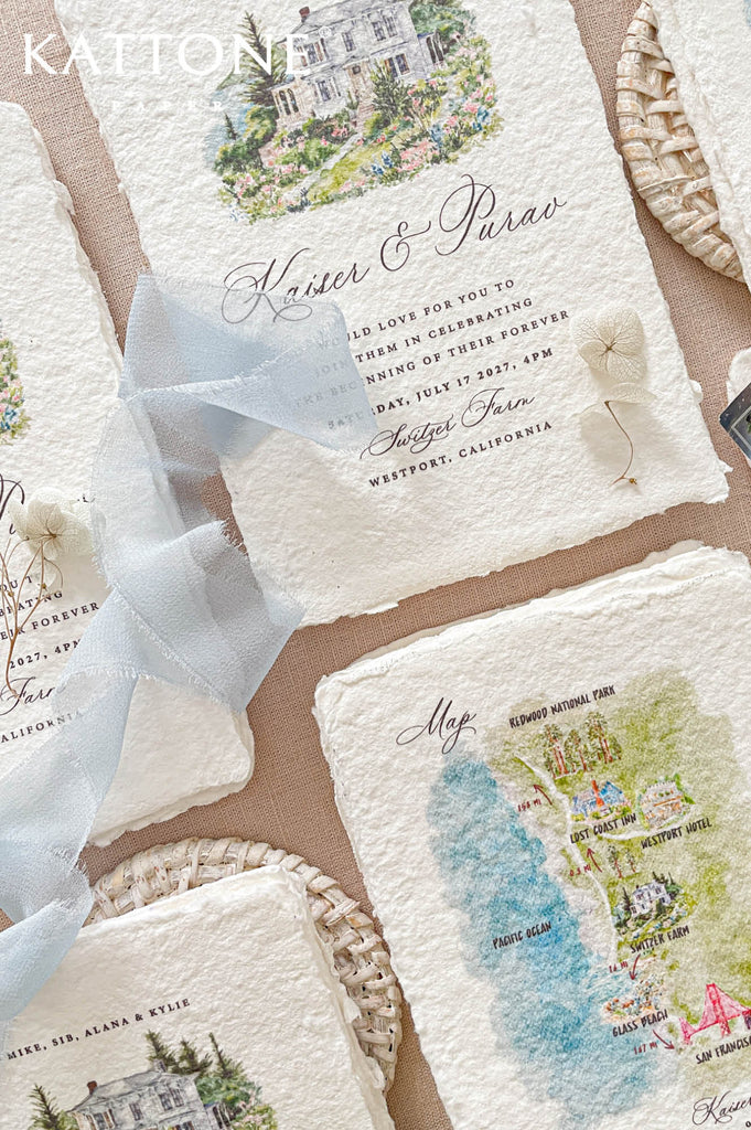 Elegant deckled edge handmade cotton paper wedding invitation featuring a custom watercolor house illustration, refined typography, and a soft dusty blue chiffon ribbon wrap.