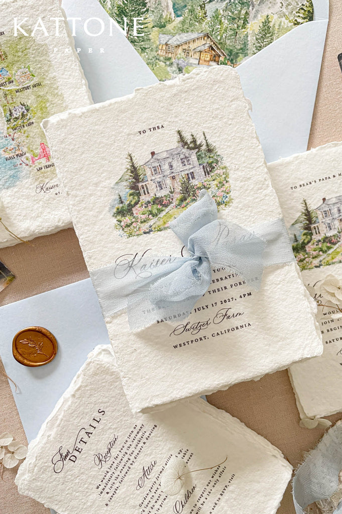 Premium handmade wedding invitation suite with custom watercolor venue illustrations, deckled edge cotton paper, scenic envelope liners, map inserts, and soft dusty blue accents for elegant destination weddings.