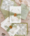 Luxury handmade cotton paper wedding invitation with deckled edges and botanical watercolor florals, styled with sage silk ribbon, wax seal and green envelopes with floral liners.