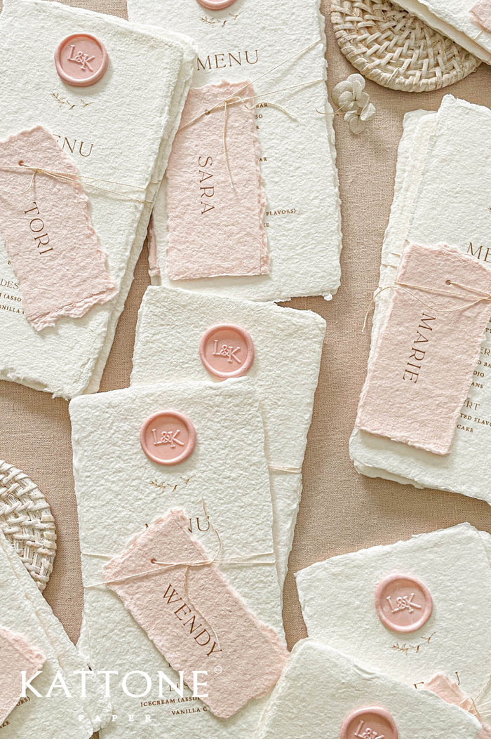 Luxury handmade paper wedding menus featuring deckled edge cotton paper, blush handmade guest name tags, wax seal detailing, and minimalist typography.
