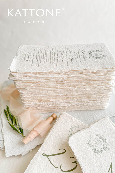 These handmade paper wedding menus capture the essence of timeless romance and artisanal elegance. Crafted from 100% cotton rag paper, each menu features naturally deckled edges and a rich, tactile texture that reflects the beauty of handcrafted design. The refined layout is elevated by a custom watercolor monogram framed in soft botanical details, bringing a delicate and personal touch to your wedding table.