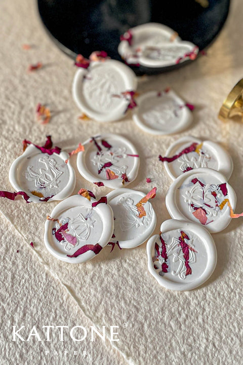 Add a romantic, handcrafted finishing touch to your stationery with these ivory botanical wax seals, delicately adorned with pressed rose petals. Each seal is individually poured and stamped, creating soft organic edges and subtle variations that enhance their artisanal character. Designed to elevate wedding invitations, envelopes, menus, and keepsakes, these wax seals bring timeless elegance and floral warmth to fine-art paper goods.