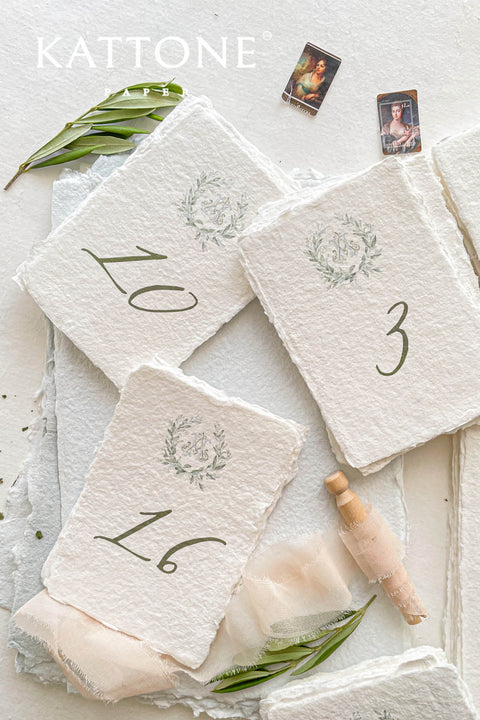 Watercolor greenery and handmade deckle-edge cotton paper create a naturally elegant table number design that brings soft, organic beauty to your wedding décor. The delicate botanical wreath and refined numeral style add a fine-art, timeless touch, making each card feel both romantic and elevated. Perfect for garden weddings, outdoor celebrations, and nature-inspired themes, this design blends airy watercolor tones with luxurious craftsmanship.