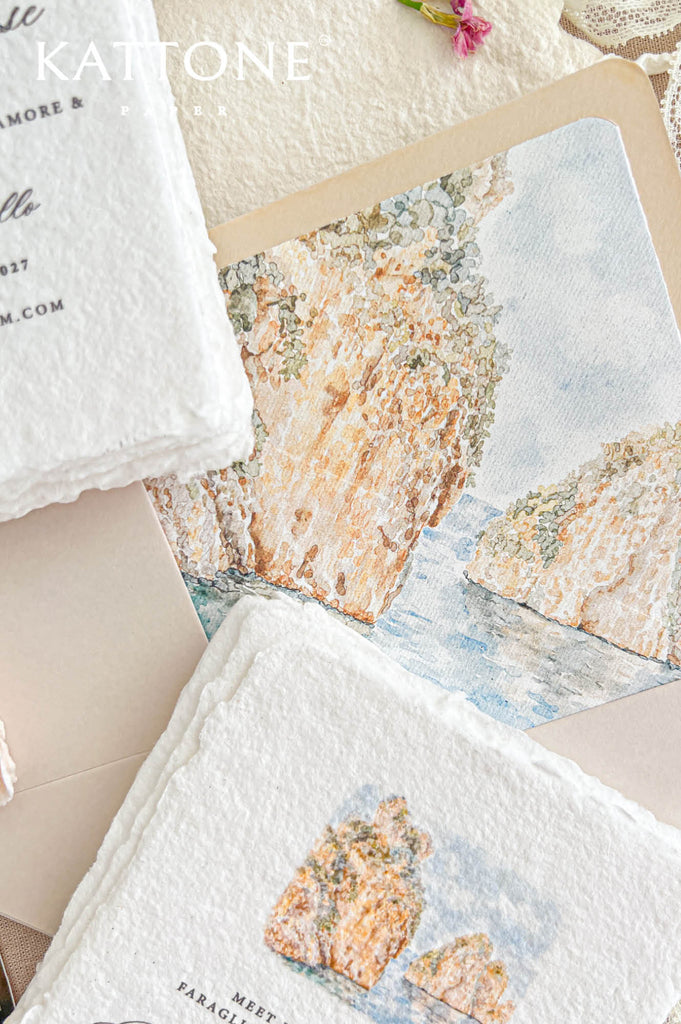 Angled close-up of a luxury champagne wedding envelope with a custom watercolor liner depicting the Faraglioni of Scopello, Sicily, featuring warm golden cliffs, muted green coastal vegetation, and tranquil Mediterranean blue waters. Coordinating ivory handmade paper wedding invitations with matching watercolor artwork and soft deckled edges are arranged beside the illustrated envelope.