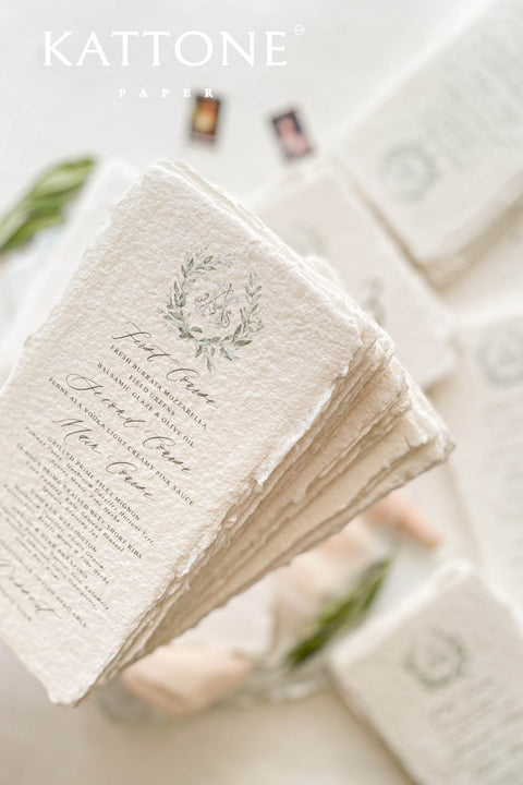 These handmade paper wedding menus capture the essence of timeless romance and artisanal elegance. Crafted from 100% cotton rag paper, each menu features naturally deckled edges and a rich, tactile texture that reflects the beauty of handcrafted design. The refined layout is elevated by a custom watercolor monogram framed in soft botanical details, bringing a delicate and personal touch to your wedding table.
