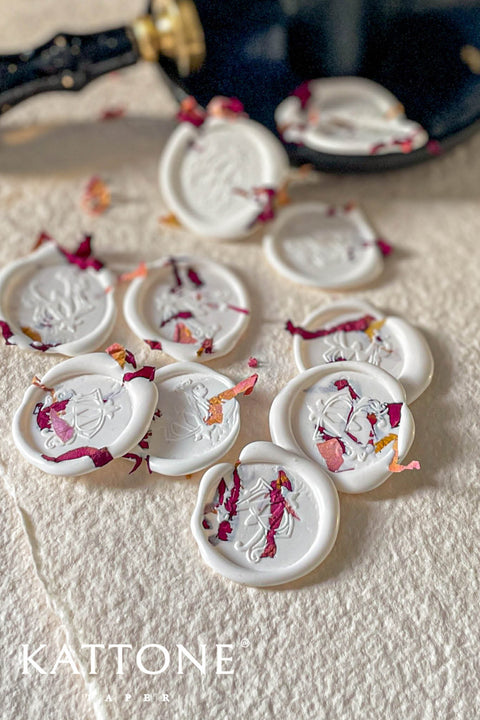 Add a romantic, handcrafted finishing touch to your stationery with these ivory botanical wax seals, delicately adorned with pressed rose petals. Each seal is individually poured and stamped, creating soft organic edges and subtle variations that enhance their artisanal character. Designed to elevate wedding invitations, envelopes, menus, and keepsakes, these wax seals bring timeless elegance and floral warmth to fine-art paper goods.
