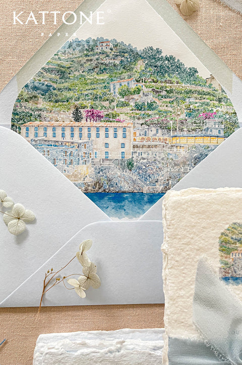 Custom wedding envelope liners with elegant watercolor coastal illustration featuring hillside architecture, lush greenery, and blue waterfront details.
