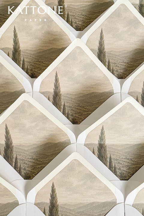 Luxury ivory wedding envelopes with custom landscape liners featuring neutral Tuscan countryside artwork in soft sepia and taupe tones.