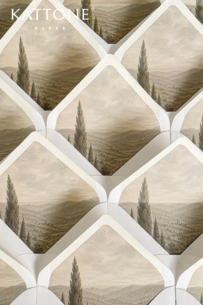 Luxury ivory wedding envelopes with custom landscape liners featuring neutral Tuscan countryside artwork in soft sepia and taupe tones.