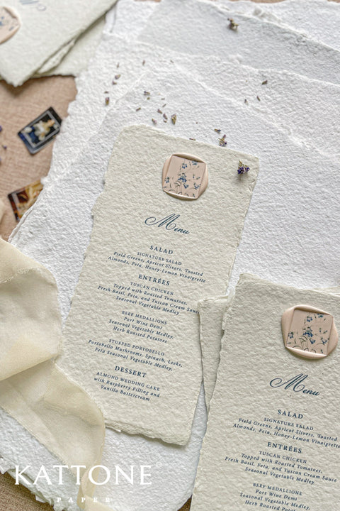 Infuse your reception with timeless artistry through our handmade paper wedding menus, featuring deckled edges, elegant typography, and floral wax seals. Each piece is crafted from soft cotton paper, offering a textured, organic finish that beautifully complements fine-art, garden, or destination weddings. Designed for couples who adore romantic, handcrafted details, these menus transform every place setting into an exquisite statement of elegance.