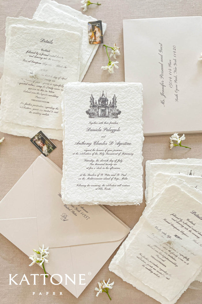 Luxury handmade cotton paper wedding invitation with deckled edges and architectural illustration, styled with neutral envelopes and coordinated stationery suite.