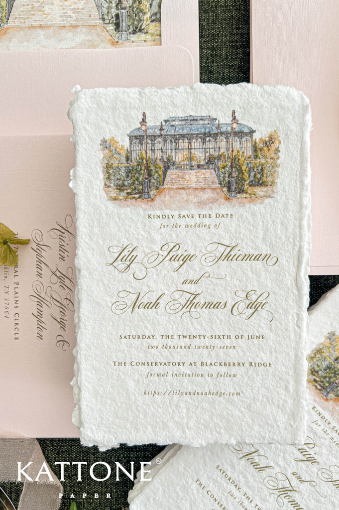 Close-up of an elegant ivory handmade paper wedding save the date card featuring a custom watercolor illustration of a glass conservatory with garden steps, vintage lampposts, and lush greenery. Gold calligraphy and classic typography complement the textured deckled paper, styled with blush pink envelopes, matching watercolor liners, and delicate botanical accents.