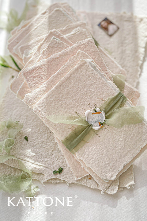 Soft, organic, and undeniably romantic - this colored handmade paper wedding invitation suite beautifully captures the essence of nature-inspired elegance. Printed on luxury blush-toned deckled-edge cotton paper, each piece is a work of art, blending timeless craftsmanship with delicate botanical elements and refined greenery details. At its heart lies a custom hand-drawn monogram, surrounded by soft watercolor foliage - a symbol of the couple’s unity and natural grace. 