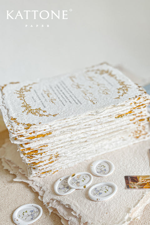 Invite your guests to your special day with the artful beauty of these exquisite handmade paper wedding invites. Perfect for a garden wedding, these invitations feature a delicate golden leaf addition, providing a touch of understated elegance and luxurious shimmer. The tactile and organic feel of the deckle edge paper creates a truly memorable keepsake, setting a romantic and refined tone for your celebration.