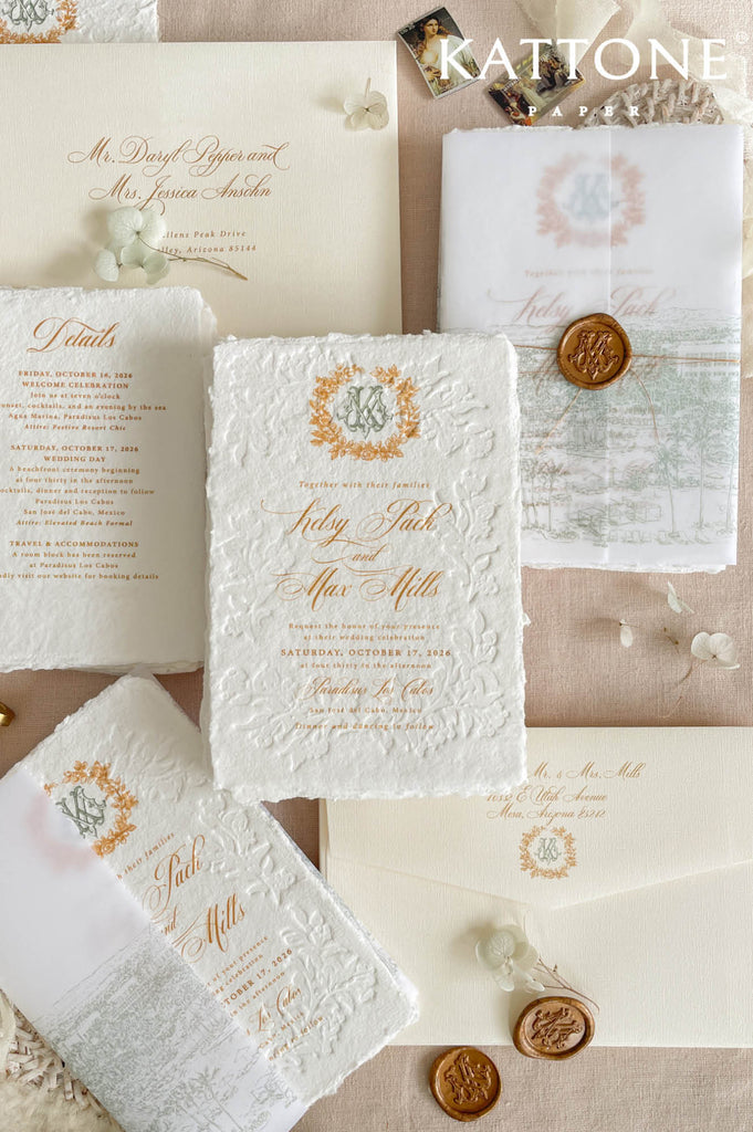 Luxury embossed handmade paper wedding invitation suite featuring deckled edge cotton paper, raised floral embossing, gold typography, custom monogram crest, vellum cover with wax seal, and coordinated ivory envelopes.