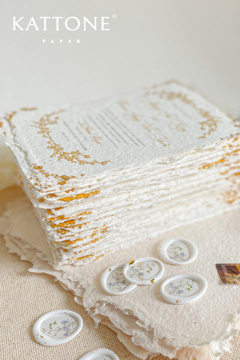 Invite your guests to your special day with the artful beauty of these exquisite handmade paper wedding invites. Perfect for a garden wedding, these invitations feature a delicate golden leaf addition, providing a touch of understated elegance and luxurious shimmer. The tactile and organic feel of the deckle edge paper creates a truly memorable keepsake, setting a romantic and refined tone for your celebration.