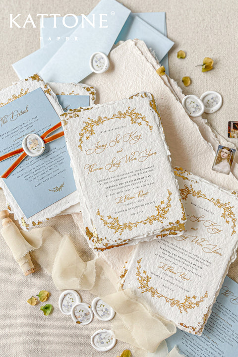 Invite your guests to your special day with the artful beauty of these exquisite handmade paper wedding invites. Perfect for a garden wedding, these invitations feature a delicate golden leaf addition, providing a touch of understated elegance and luxurious shimmer. The tactile and organic feel of the deckle edge paper creates a truly memorable keepsake, setting a romantic and refined tone for your celebration.