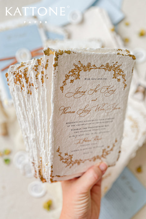 Invite your guests to your special day with the artful beauty of these exquisite handmade paper wedding invites. Perfect for a garden wedding, these invitations feature a delicate golden leaf addition, providing a touch of understated elegance and luxurious shimmer. The tactile and organic feel of the deckle edge paper creates a truly memorable keepsake, setting a romantic and refined tone for your celebration.