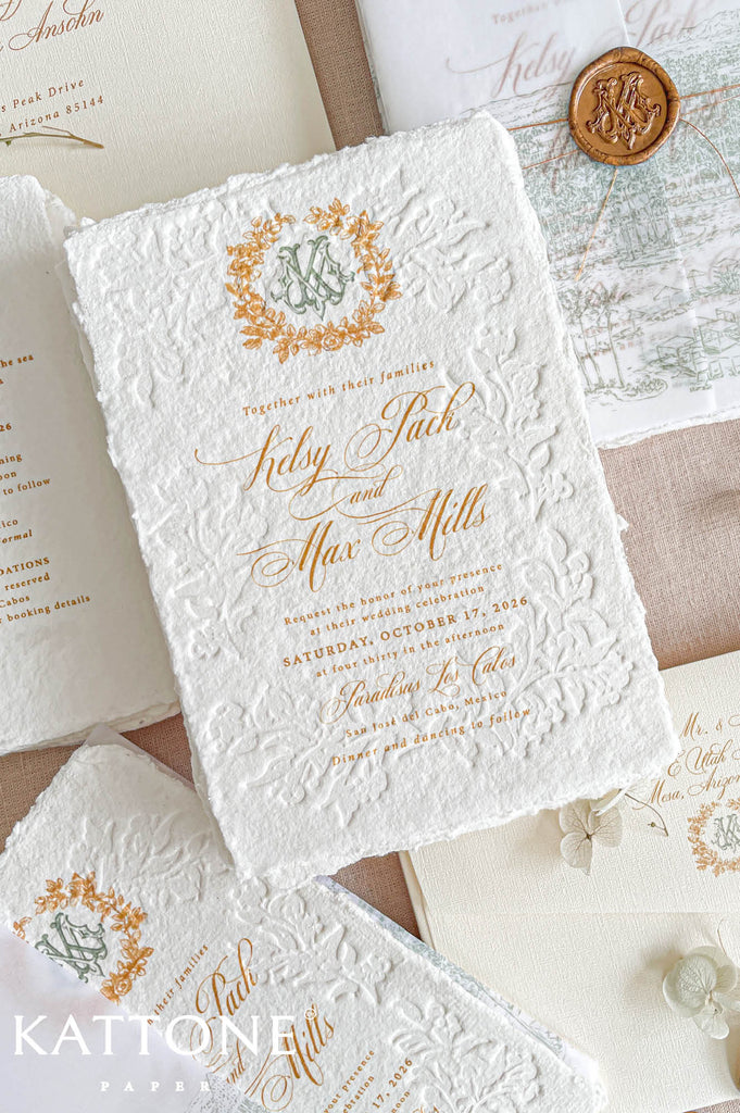 Romantic flat lay of luxury wedding stationery showcasing embossed handmade paper invitations, details cards, vellum covers, wax seal accents, monogram elements, and matching ivory envelope styling.