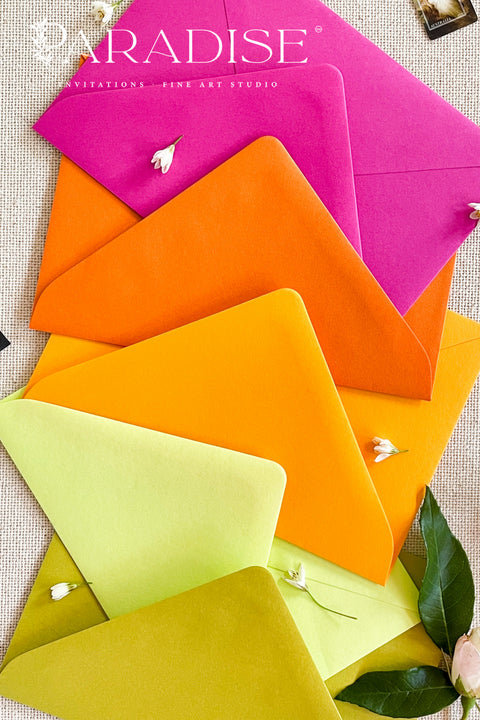 Different colored envelopes arranged in a vibrant flat lay, showcasing pink, orange, yellow, and green tones on textured linen background.