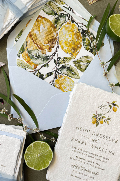 Close-up of handmade cotton paper wedding invitation featuring textured deckle edges and delicate watercolor lemon artwork.