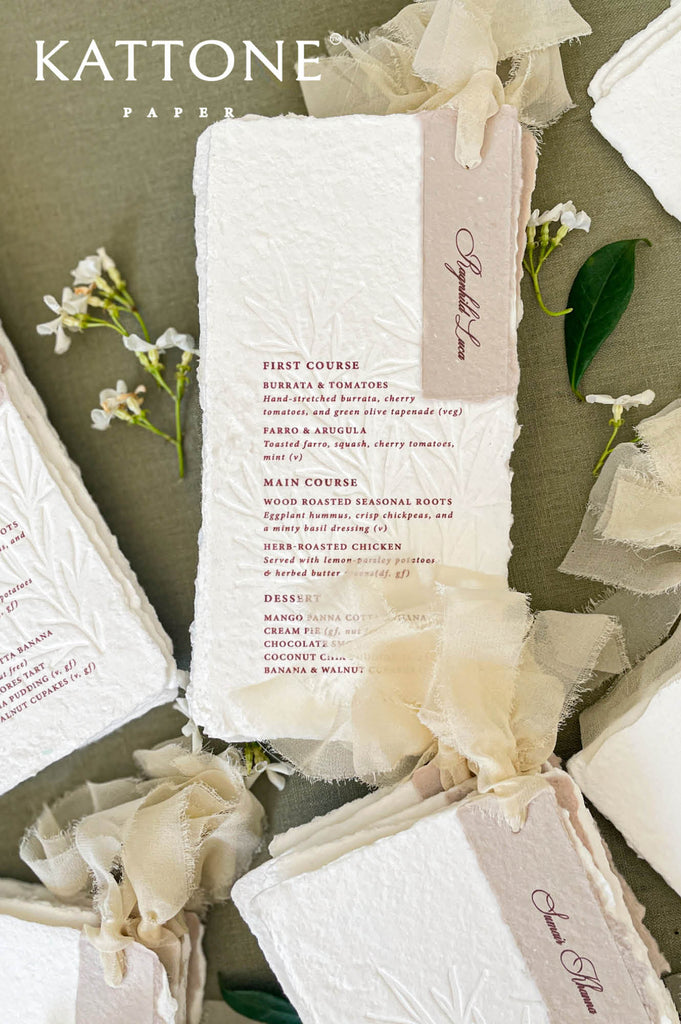 Handmade paper wedding menus tied with soft ribbon for an elegant reception table presentation.