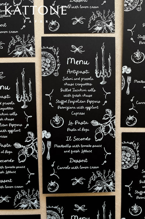 Black wedding menus with whimsical hand-drawn wedding icons and white typography, styled for a modern reception.