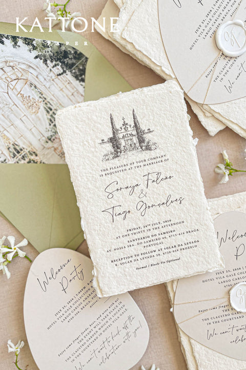 Romantic wedding stationery styling with greenery, handmade paper, and custom watercolor venue invitations.