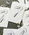 Embossed handmade paper table numbers with deckle edges and elegant calligraphy, styled for a wedding reception.