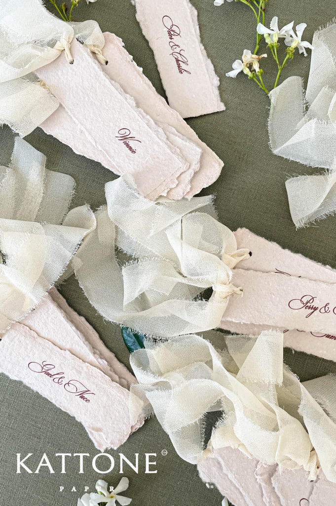Blush handmade wedding place cards tied with soft ribbon for romantic table décor.