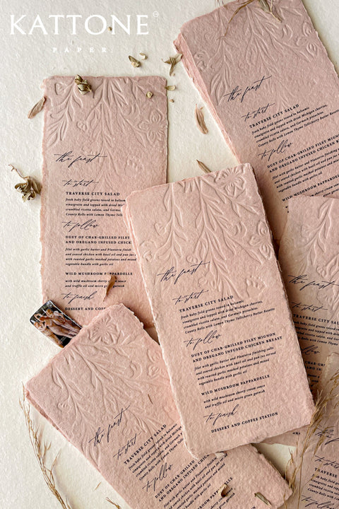 These embossed handmade wedding menus are a striking fusion of texture, color, and craftsmanship - designed to make a refined statement at your celebration. Crafted from luxurious cotton rag paper and tinted in a soft, romantic blush hue, each menu features an intricate embossed botanical design that adds depth and dimension. 