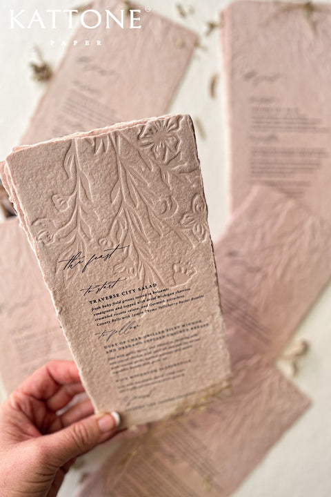 These embossed handmade wedding menus are a striking fusion of texture, color, and craftsmanship - designed to make a refined statement at your celebration. Crafted from luxurious cotton rag paper and tinted in a soft, romantic blush hue, each menu features an intricate embossed botanical design that adds depth and dimension. 