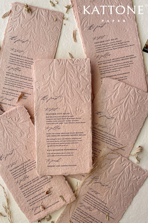 These embossed handmade wedding menus are a striking fusion of texture, color, and craftsmanship - designed to make a refined statement at your celebration. Crafted from luxurious cotton rag paper and tinted in a soft, romantic blush hue, each menu features an intricate embossed botanical design that adds depth and dimension. 